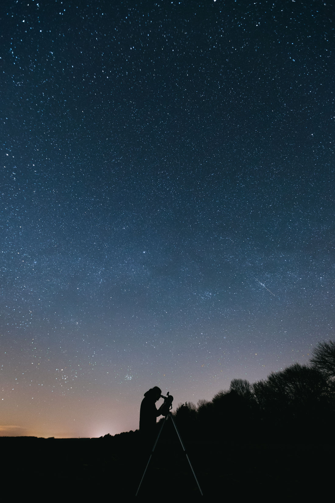 Man silhouetted against a starry night sky using a telescope — telescope mount guide for beginners