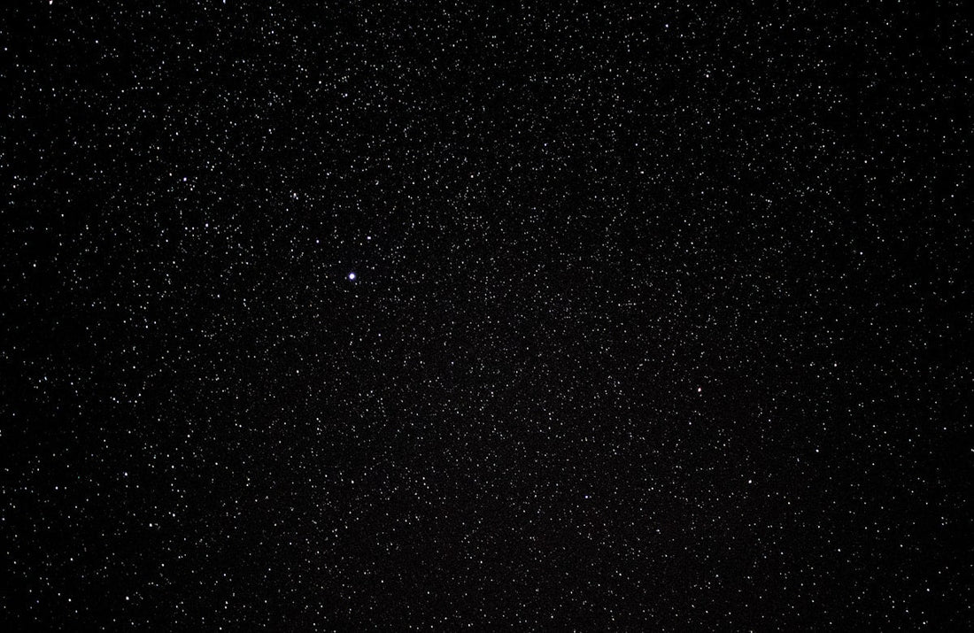 Bright Perseid meteor streaking across a dark starry night sky over an open landscape — Perseid meteor shower 2026 viewing guide