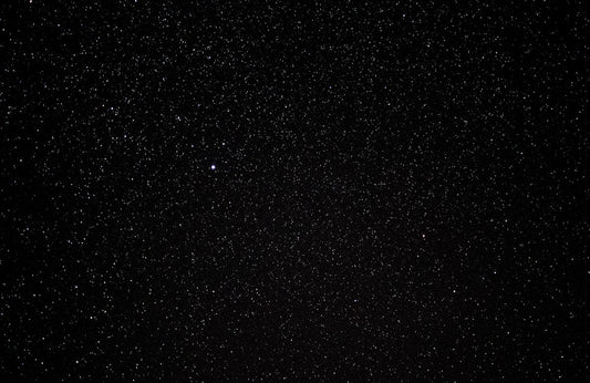 Bright Perseid meteor streaking across a dark starry night sky over an open landscape — Perseid meteor shower 2026 viewing guide