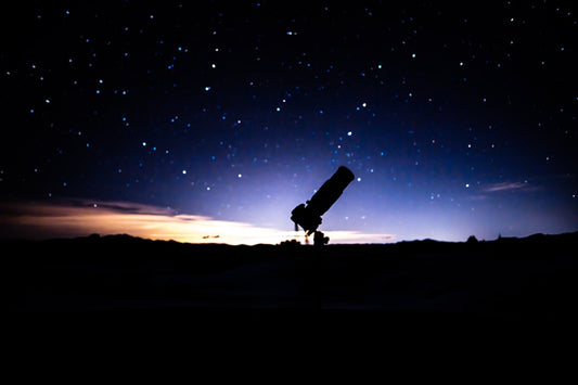 Beginner telescope on a tripod under a starry night sky — how to photograph the Moon with a smartphone through a telescope