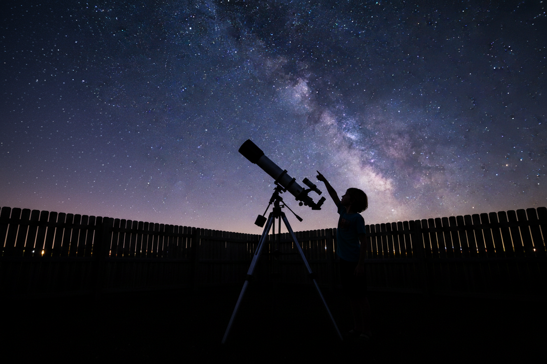 Silhouette of child using beginner telescope in backyard under starry night sky - best telescope for kids ages 6-14